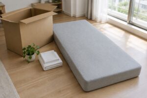 段ボール箱の横に置いた厚いグレーのマットレス
